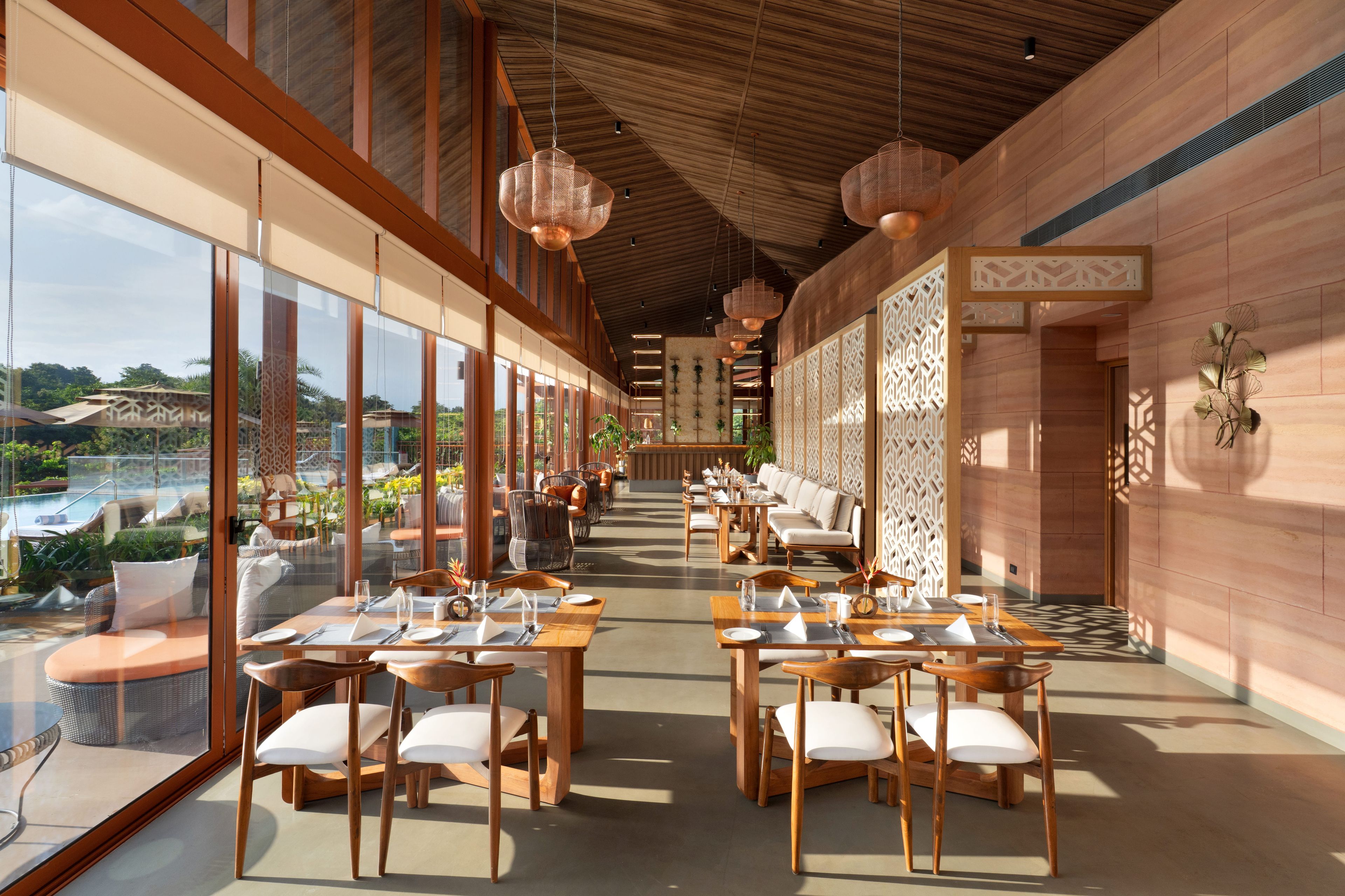 Un comedor espacioso con mesas y sillas largas, ventanas grandes y vistas al exterior.