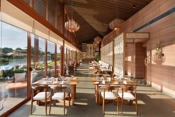 A spacious dining area with long tables and chairs, large windows, and a view of the outdoors. - Miros Neral - Foothills of Matheran (Karjat)