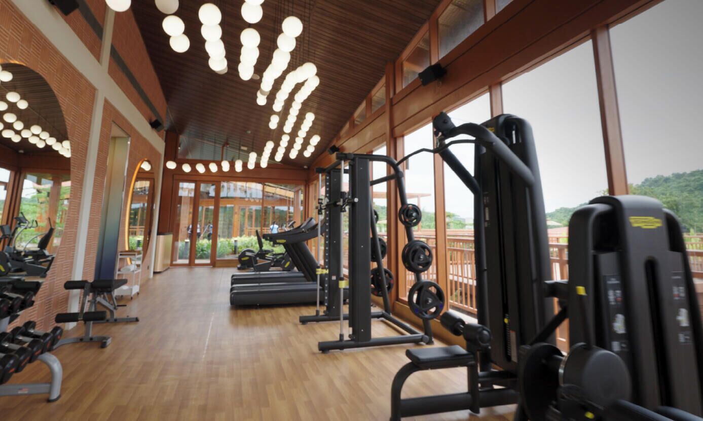 A gym with treadmills, weight machines, and a large window overlooking greenery.