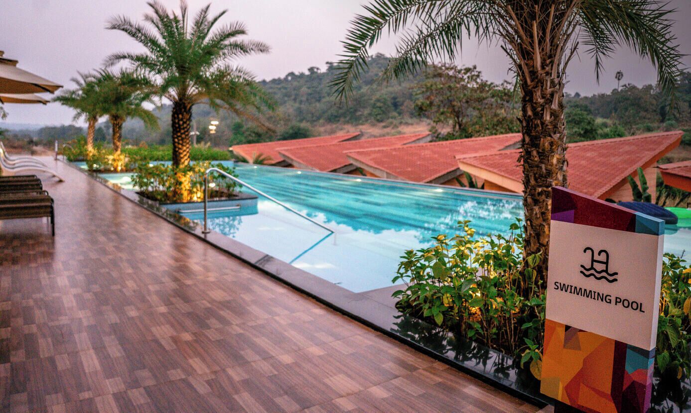 A swimming pool with a wooden deck and palm trees.