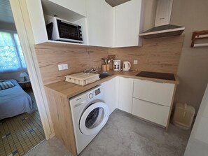 Une petite cuisine équipée d’un four à micro-ondes, d’une machine à café et d’un lave-linge.