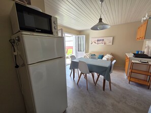 A compact kitchen with a refrigerator, microwave, and a dining area with a table and chairs. - House near the beach - 4 guests (La Tranche-sur-Mer)