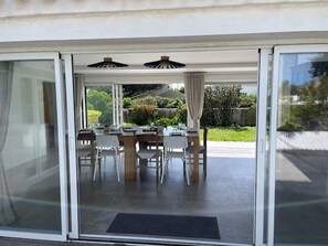 Un espace patio avec une table et des chaises, une porte vitrée et une vue sur la verdure.