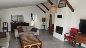 A spacious living room with a fireplace, a glass coffee table, and a wooden TV stand. - Comfortable house, pets welcome - 10 guests (Noirmoutier-en-l'Île)