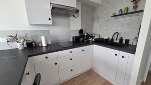 A modern kitchen with white cabinets, a black countertop, and a wooden floor.