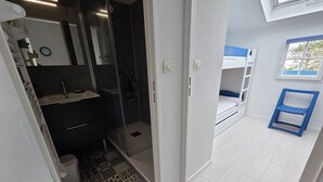 A bathroom with a shower, a sink, and a toilet. There is a patterned rug on the floor.