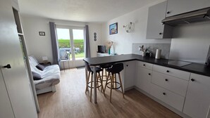 A modern kitchen with a dining area, a sofa, and a view of the garden.