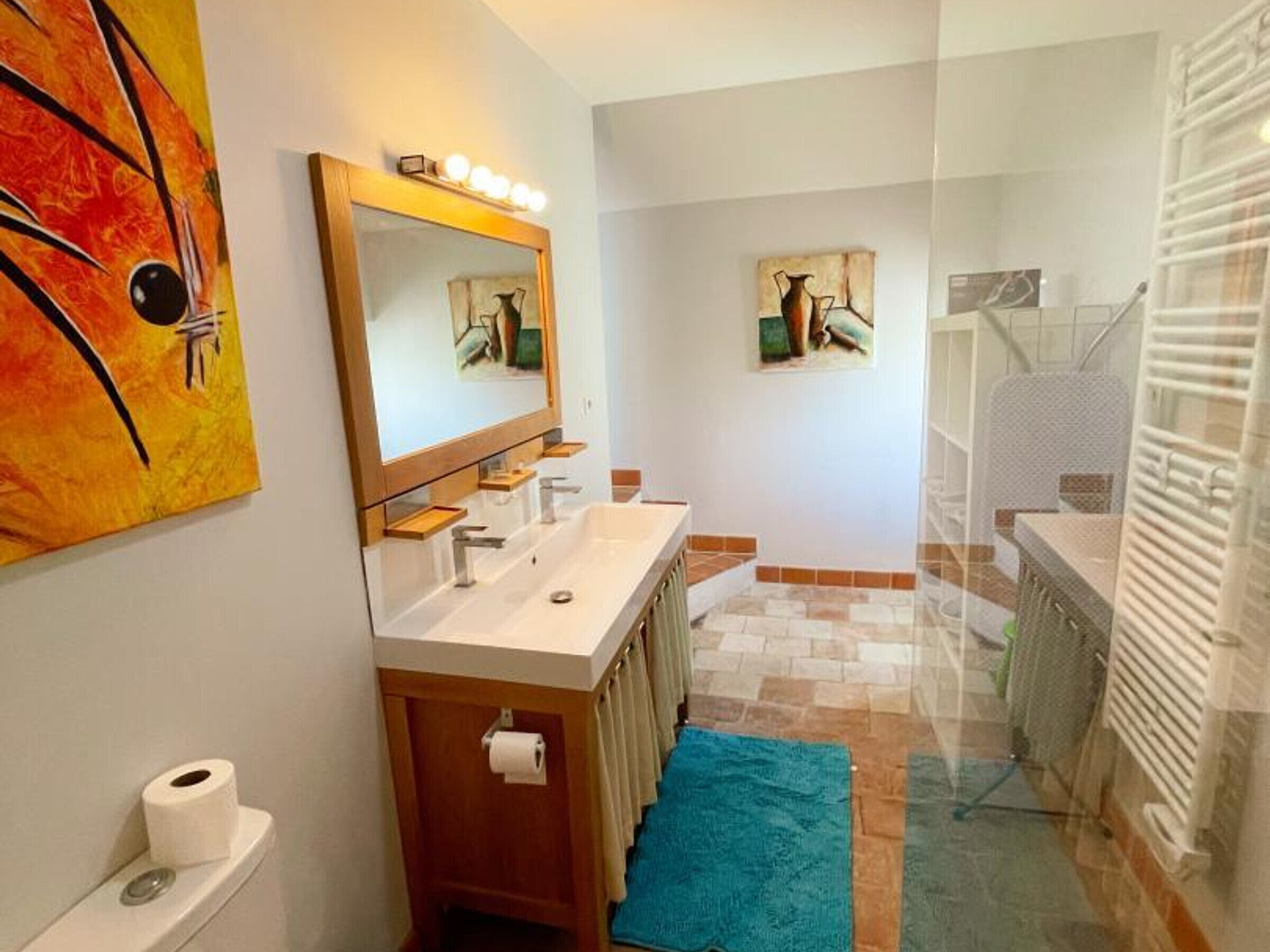 Ein Badezimmer mit Doppelwaschbecken, Spiegel, Toilette und Duschbereich.