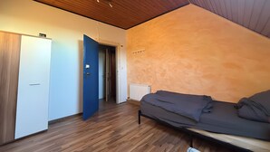 A bedroom with a wooden ceiling, a bed, a wardrobe, and a door leading to another room. - Spacious & Comfortable House – Perfect for Workers or Holiday Guests (Orbis)