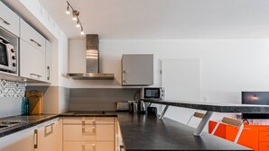 Een moderne keuken met witte kastjes, een roestvrijstalen afzuigkap, een magnetron en een broodrooster.