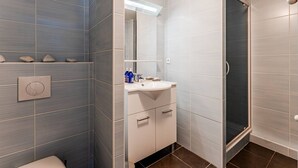 Een badkamer met toilet, wastafel, spiegel en douche.