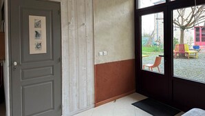 Una habitación con puerta de madera, ventana con vistas al exterior y un felpudo.
