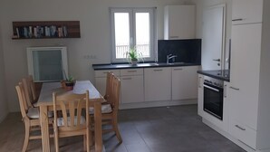 A modern kitchen with white cabinets, a black countertop, and a dining table with wooden chairs.