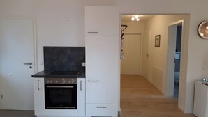 A compact kitchen with a black stove top, a built-in oven, and a white refrigerator.