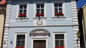 A building with three windows, a central door, and flower boxes on the upper windows.