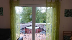 Ein Zimmer mit einer Schiebetür und Zugang zu einer Terrasse, auf der ein Tisch und Stühle stehen.