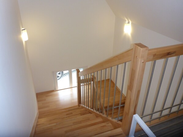 A wooden staircase with metal railings, white walls, and two wall-mounted lights. - Cozy Apartment in the Historic Center of Schlüsselfeld (Schlüsselfeld)