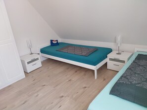 Ein Schlafzimmer mit einem Einzelbett, einem Nachttisch und einem Fenster.