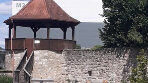 Ein Gazebo mit Steinmauer, einer Fontäne und Holzstatuen.