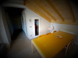 Una stanza con un tavolo giallo, pareti bianche e un soffitto in legno.