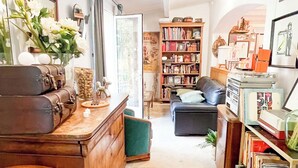 Ein geräumiges Wohnzimmer mit einem grünen Sofa, einem Holztisch und einem Bücherregal voller Bücher und Dekoration.
