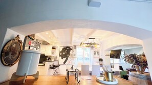 A modern interior with an arched doorway leading to a kitchen area, a dining table with chairs, and a decorative vase on the table. - Maison d'Artiste Provence 8p Piscine Jacuzzi between Aix, Luberon, Verdon & Cassis (Jouques)