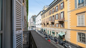 A narrow street with parked scooters and bicycles, buildings with balconies, and a clear sky. - Italianway Comfort - Dell'orso 9 (Milan)