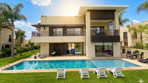 A modern two-story house with a swimming pool, outdoor seating, and a well-maintained lawn.