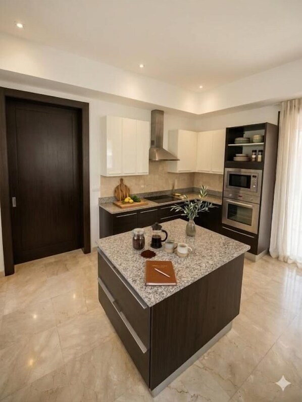 A modern kitchen with a central island, dark cabinetry, and built-in appliances.