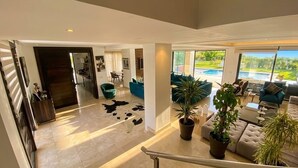 A spacious living area with a pool view, a staircase, and modern furnishings.