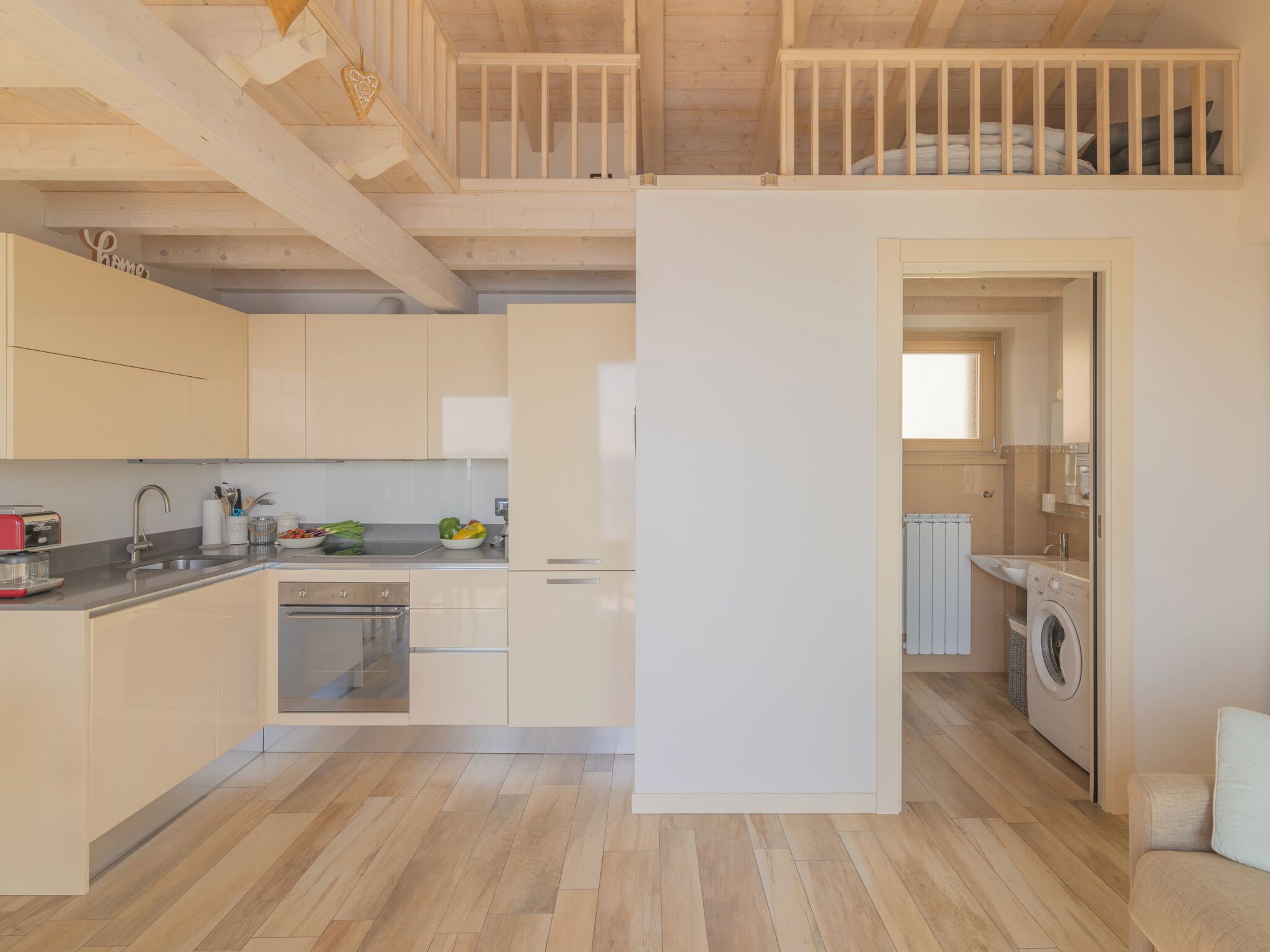 A modern kitchen with wooden beams, a dining area, and a laundry room.