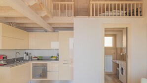 Cozinha moderna com vigas de madeira, área de refeições e lavanderia.