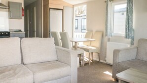 Um quarto aconchegante com um sofá, uma mesa pequena e uma janela com cortinas.