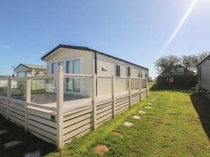 A mobile home with a fenced deck and a small porch.