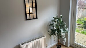 Una habitación con un radiador, una ventana que da a un jardín y un objeto decorativo en la pared.