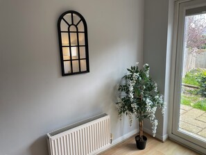 Ein Zimmer mit Heizkörper, einem Fenster mit Gartenblick und einem an der Wand befestigten Dekorationselement.