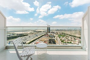 A balcony with a view of a cityscape, a white chair, and a small round table. - PVH - Al Jawhara - Charming Studio (Dubai)