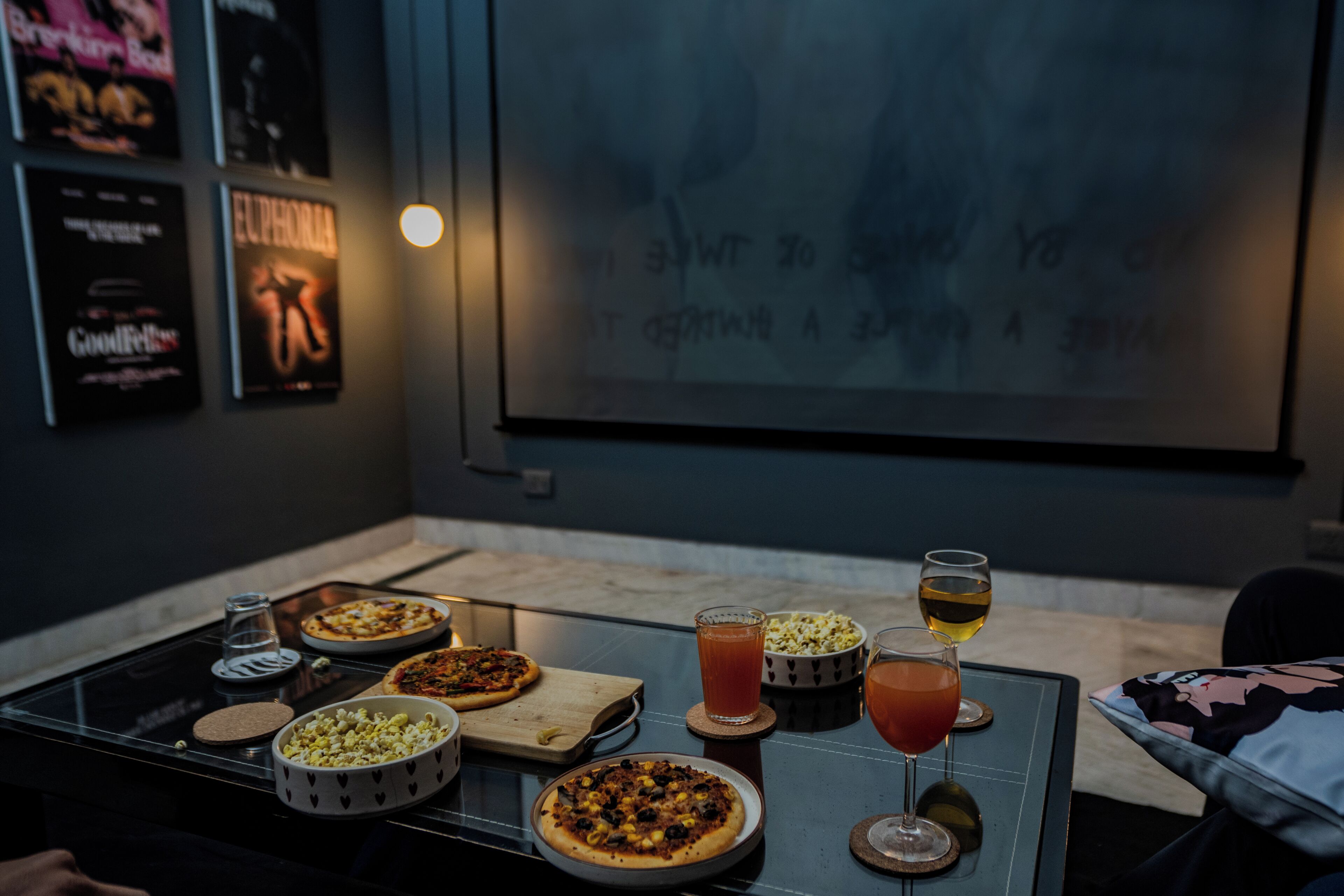A dining table with pizzas, drinks, and a bowl of popcorn.