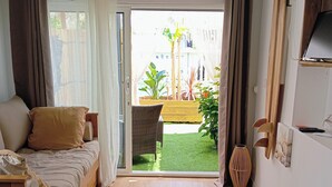 Una habitación con cama, piso de madera, vista a un jardín y puerta corrediza de vidrio.