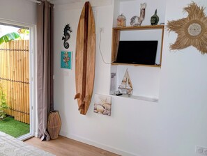 Ein Zimmer mit einem Holzsurfbrett, einer Seepferdchen-Dekoration, einem gerahmten Bild, einem kleinen Segelbootsmodell und einem gewebten Wandbild.