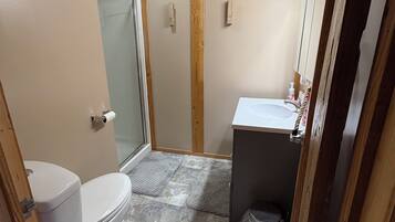 A small bathroom with a toilet, a shower, and a sink.