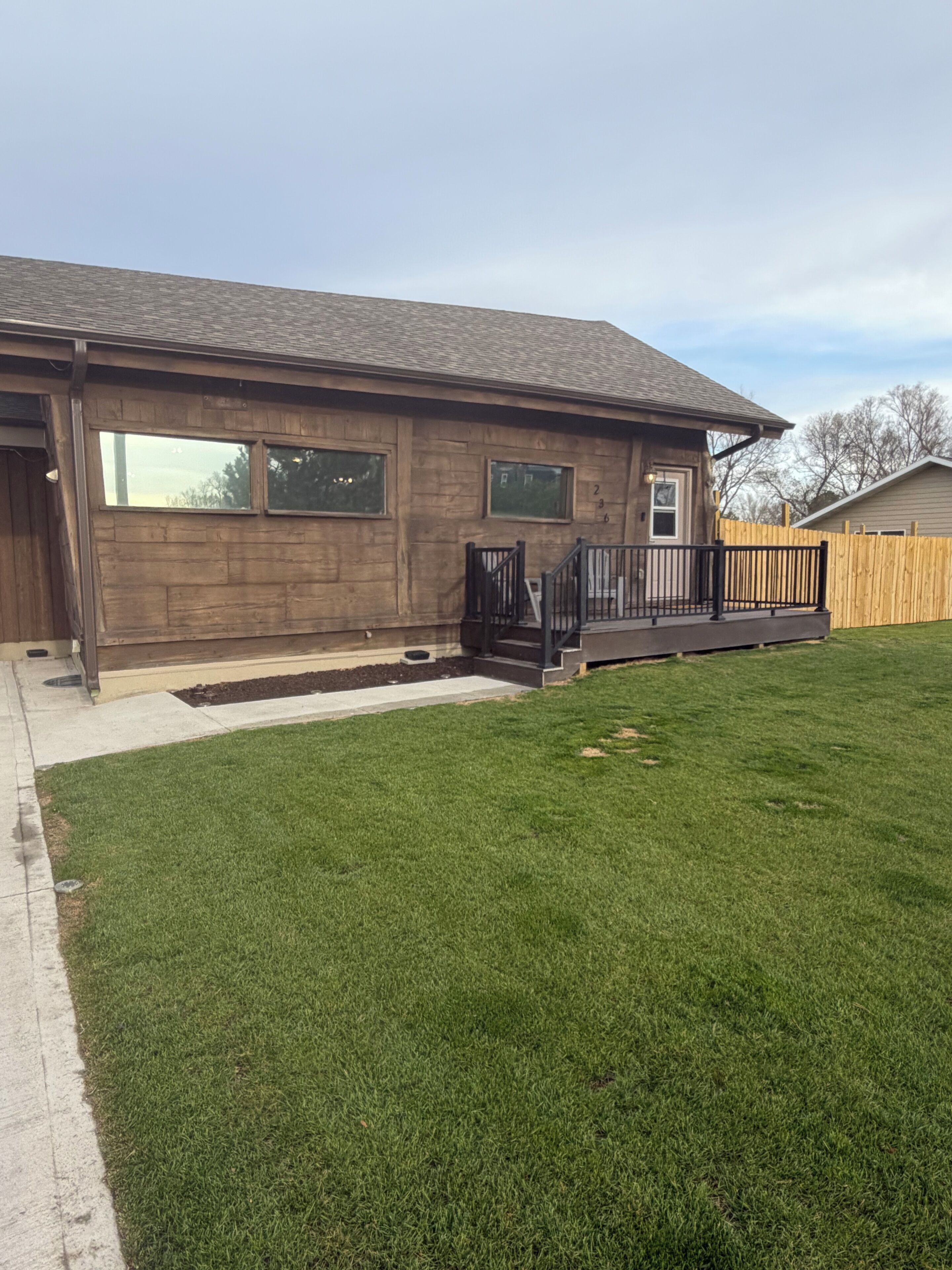A single-story house with a front porch, a fenced yard, and a well-maintained lawn.