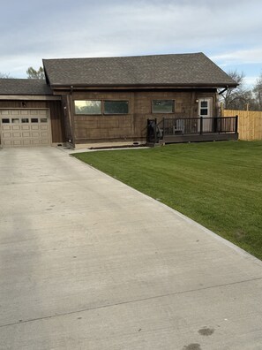 A residential house with a garage, a front porch, and a well-maintained lawn.