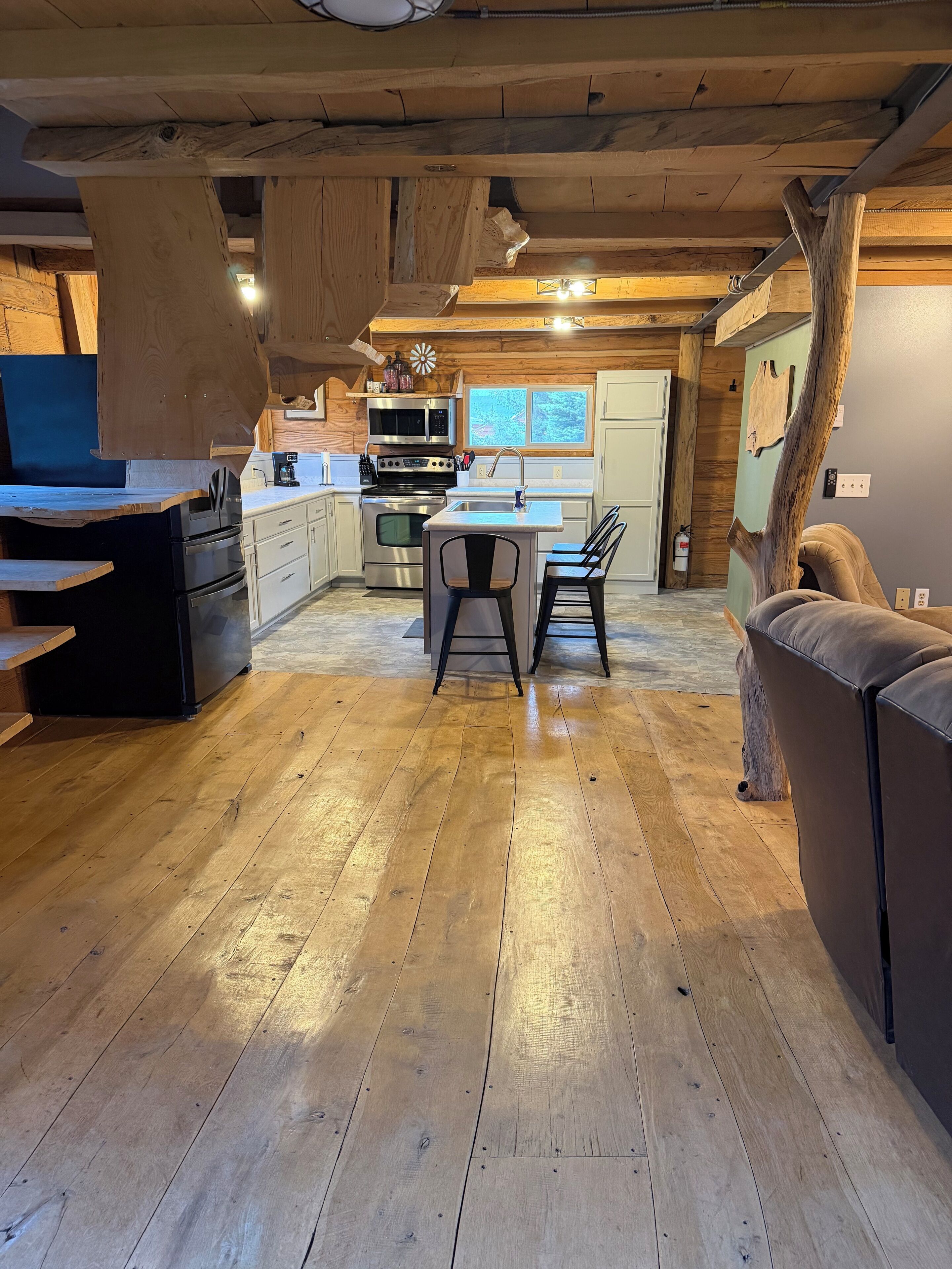 Una cocina amplia con piso de madera, una isla central con sillas y electrodomésticos modernos.