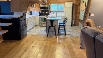 Una cocina amplia con piso de madera, una isla central con sillas y electrodomésticos modernos.