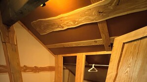 A bedroom with a bed, wooden ceiling beams, a closet, and a small staircase.