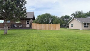 A residential property with a well-maintained lawn, a wooden deck, and a fenced backyard.
