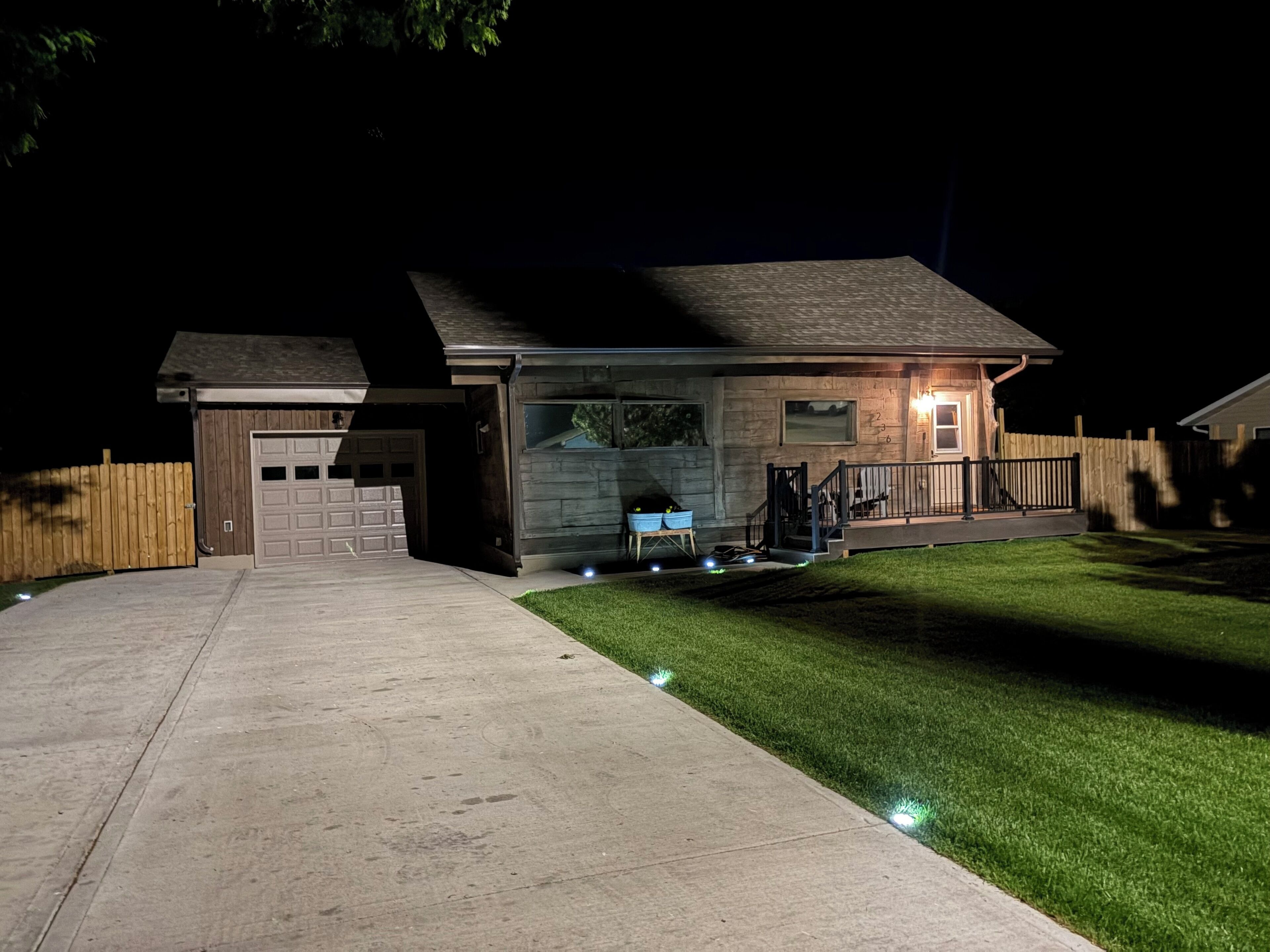 Une maison d’habitation avec un garage, une véranda et une pelouse bien entretenue.