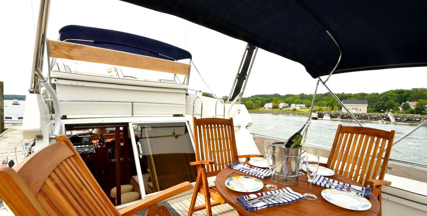 A dining table with chairs, a bottle of champagne, and plates on a boat.