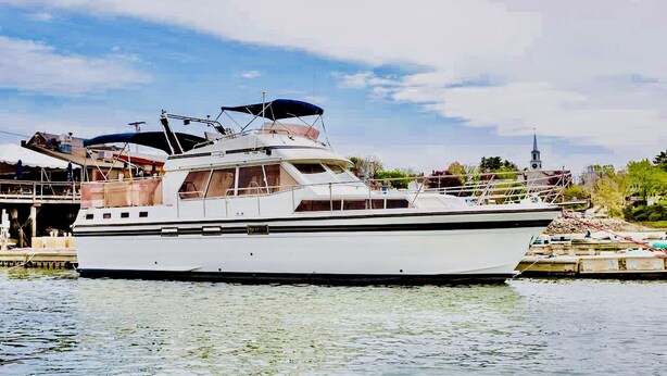 Un grand yacht blanc était amarré dans une marina, sous un ciel dégagé, avec une église en arrière-plan.